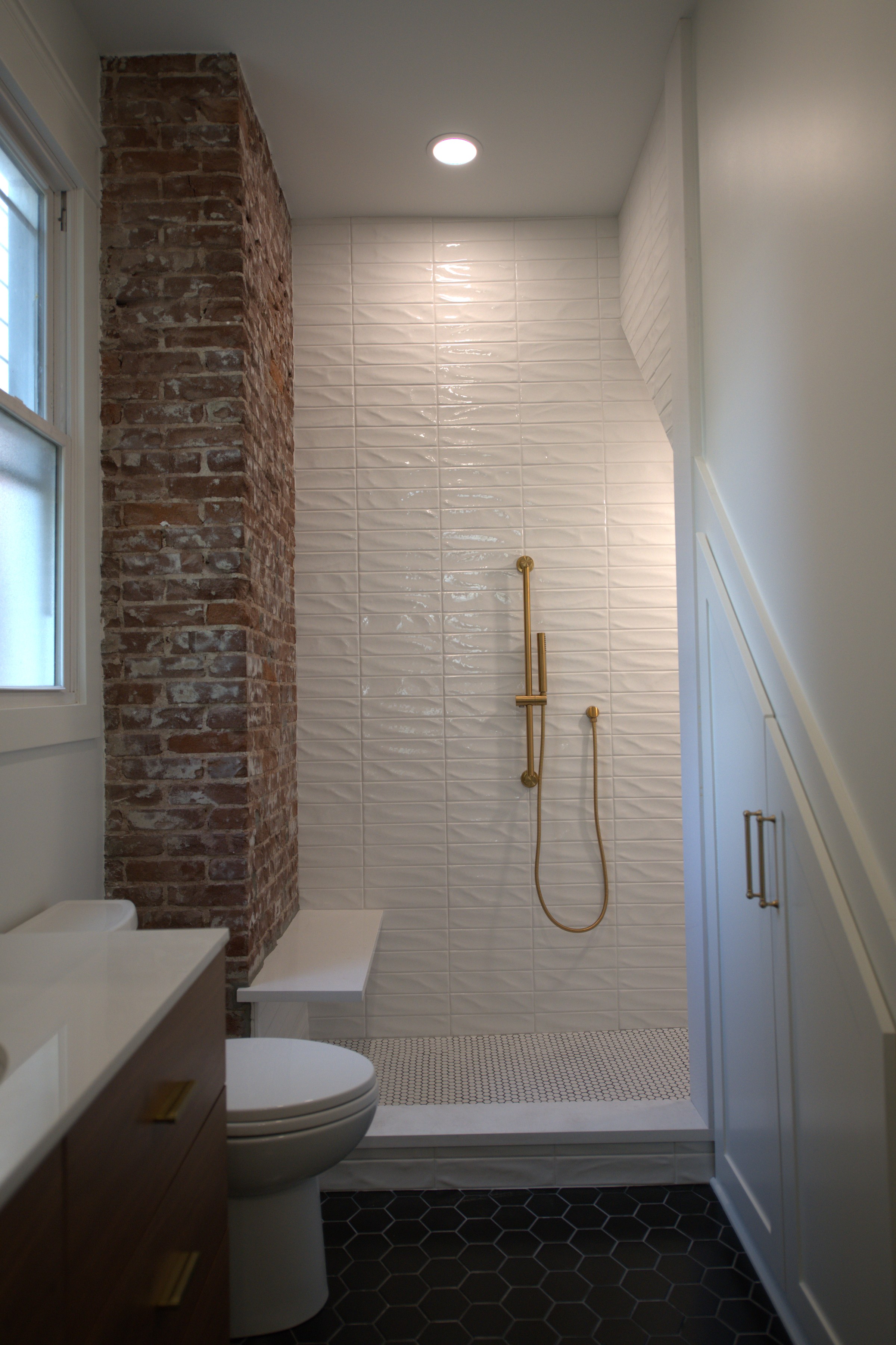 Walk-in shower with brick accent wall and brass shower